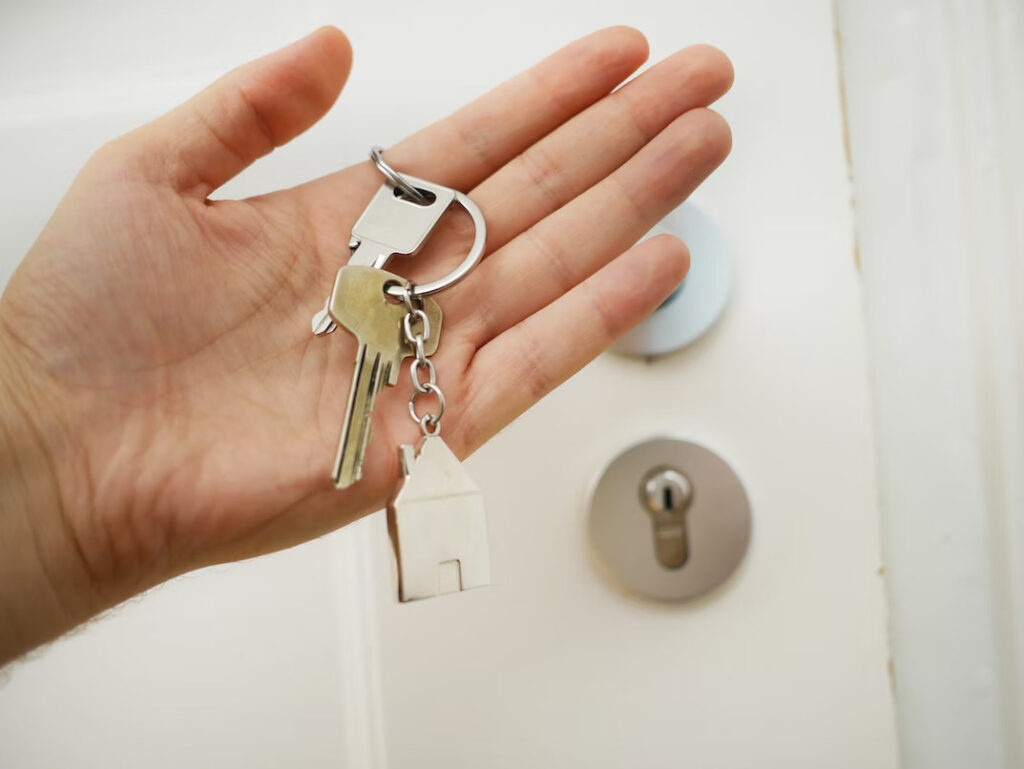 a hand holding some house keys with a house-shaped keychain
