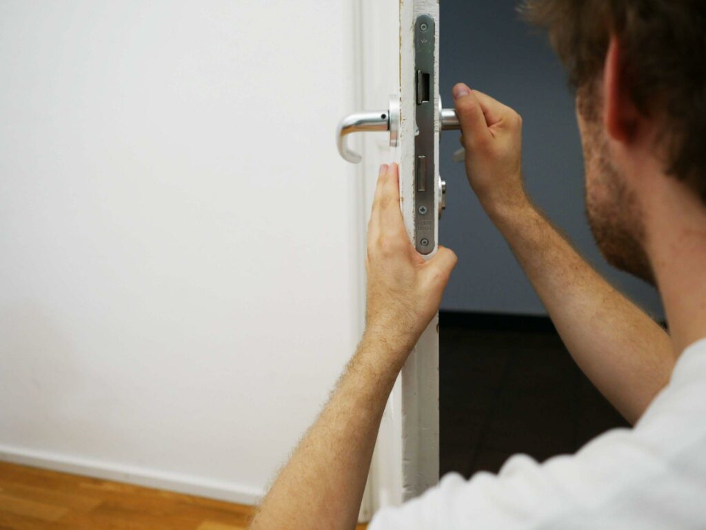 man in a white shirt installing a door lock
